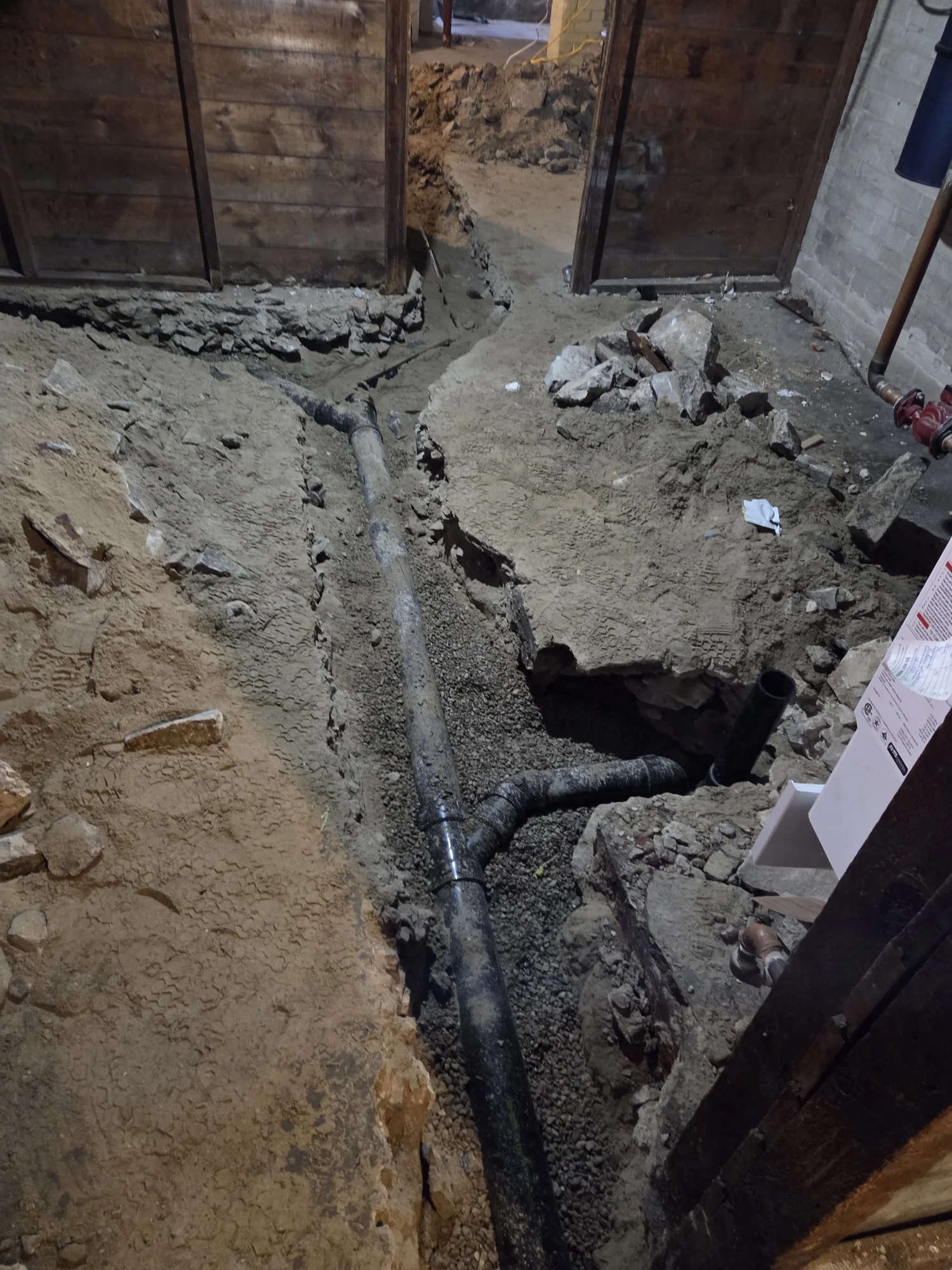 Drain junction installation beneath an opened basement floor