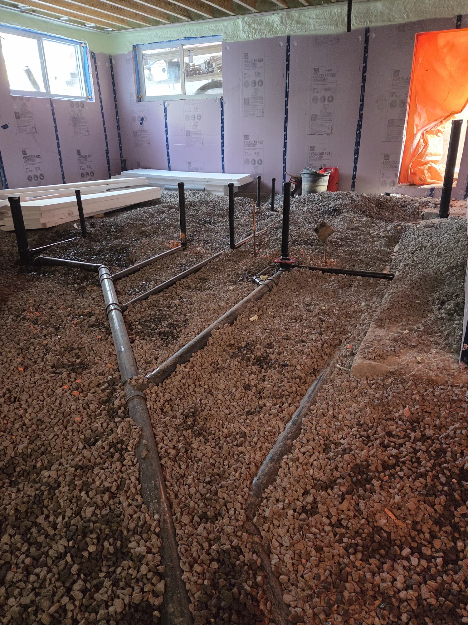 Wide view of basement drain pipes before the slab