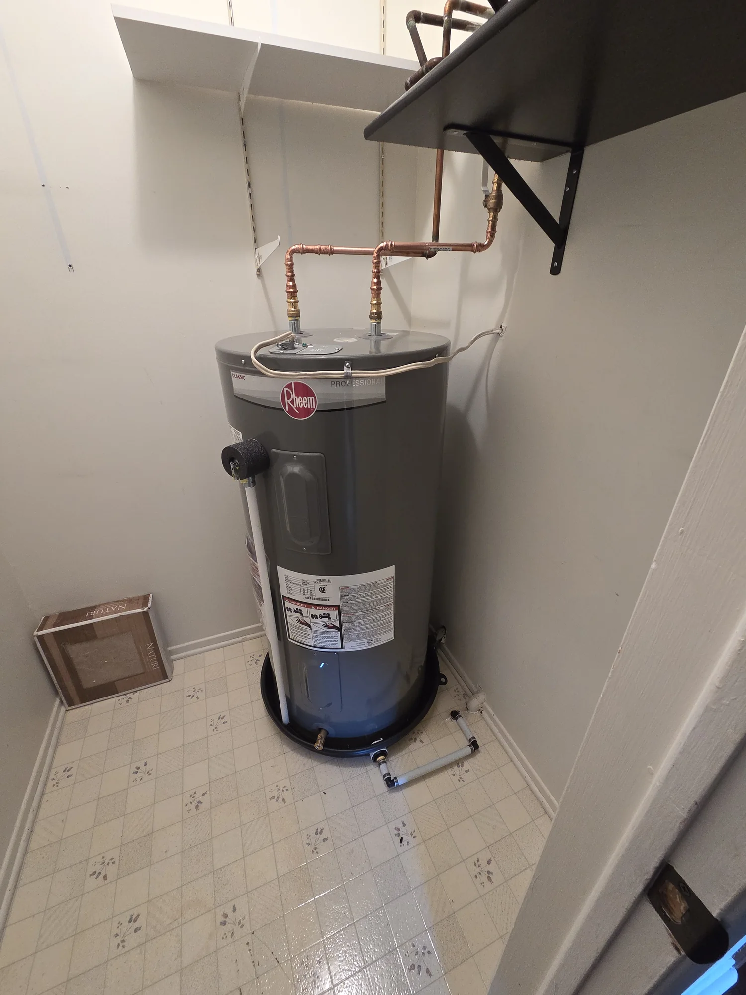 Electric water heater connected to copper pipes in a utility room