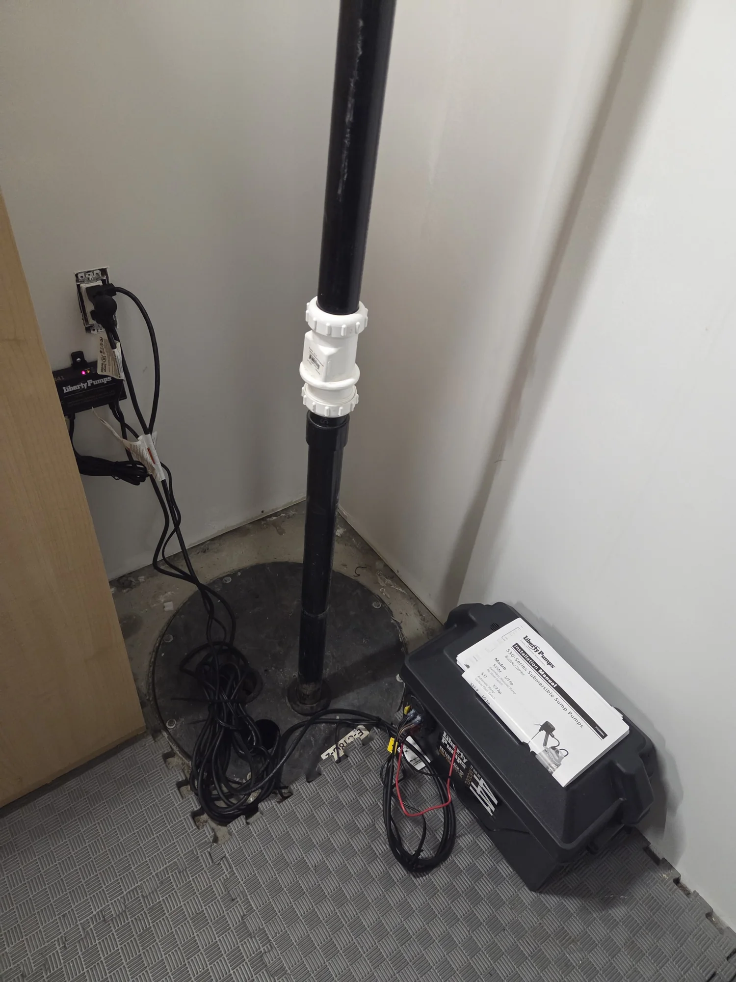 Sump pump and battery backup beside a basement sump pit