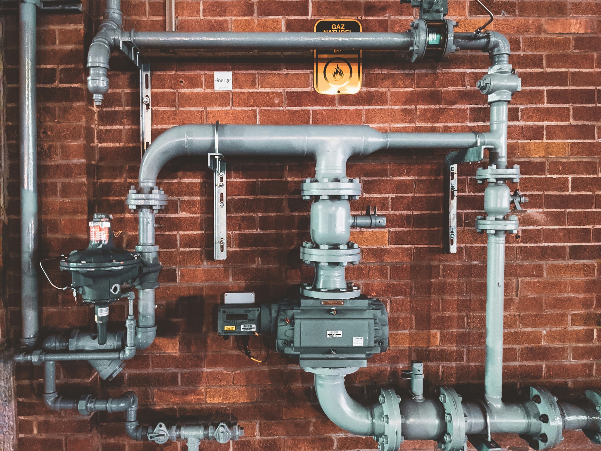 Commercial building water meters and large service piping on a brick wall