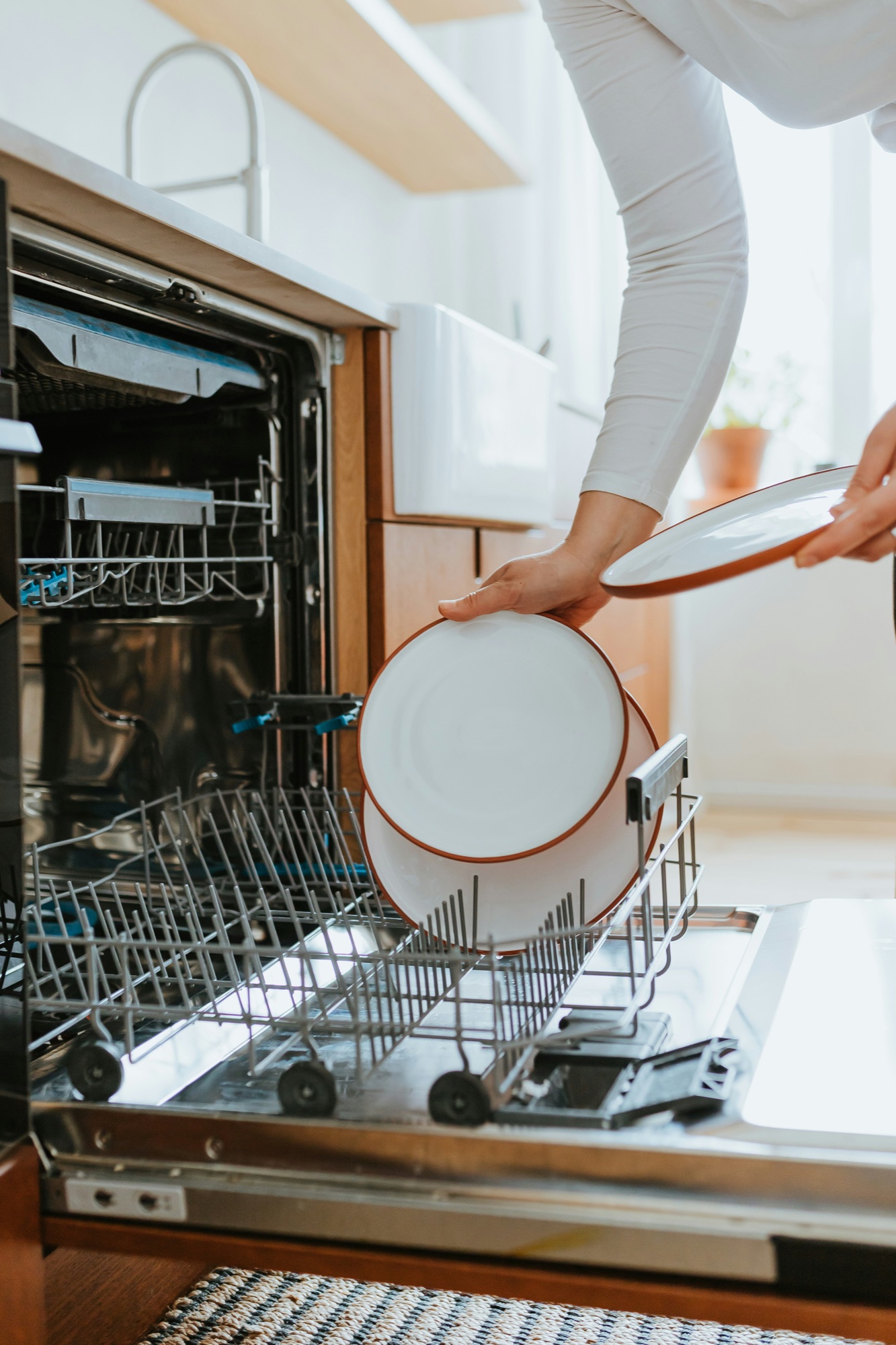 A dishwasher being loaded in a bright kitchen