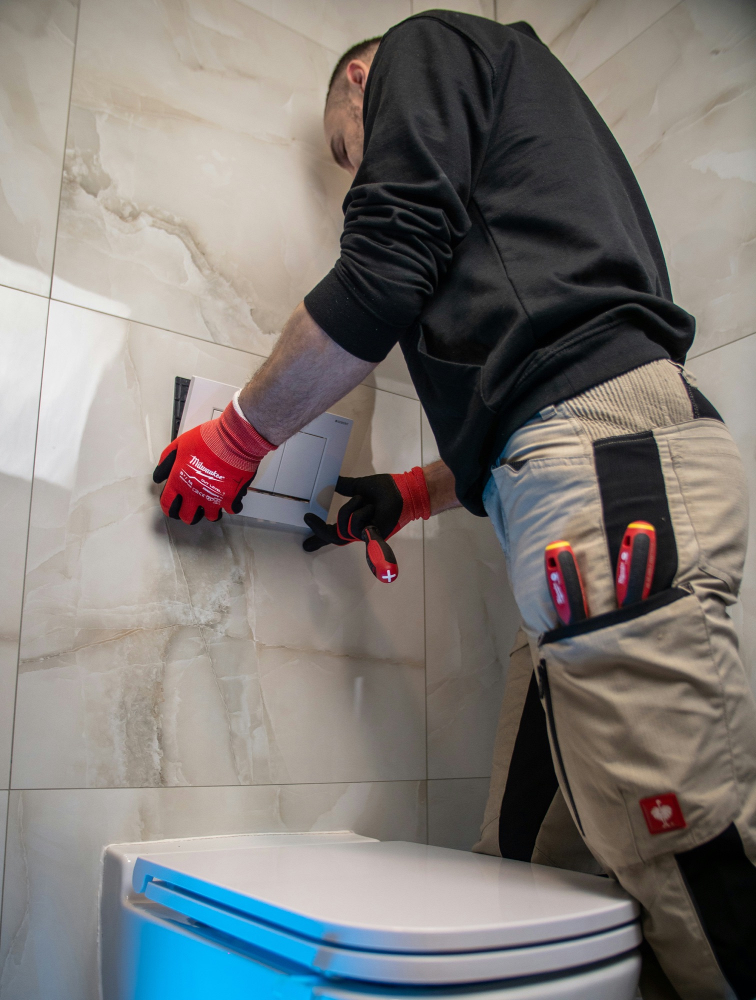 A plumber working on a concealed toilet installation