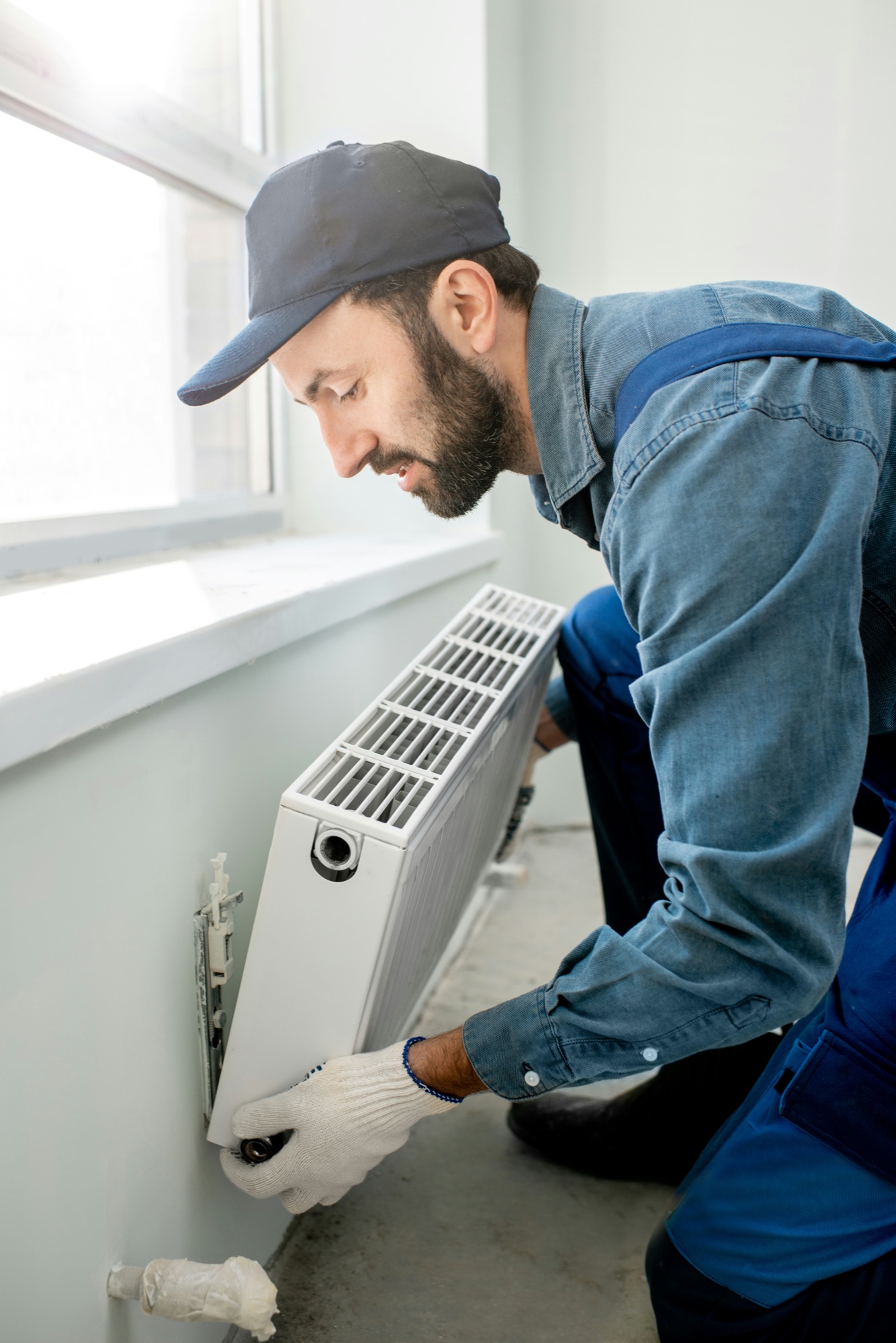 A plumber servicing a residential radiator